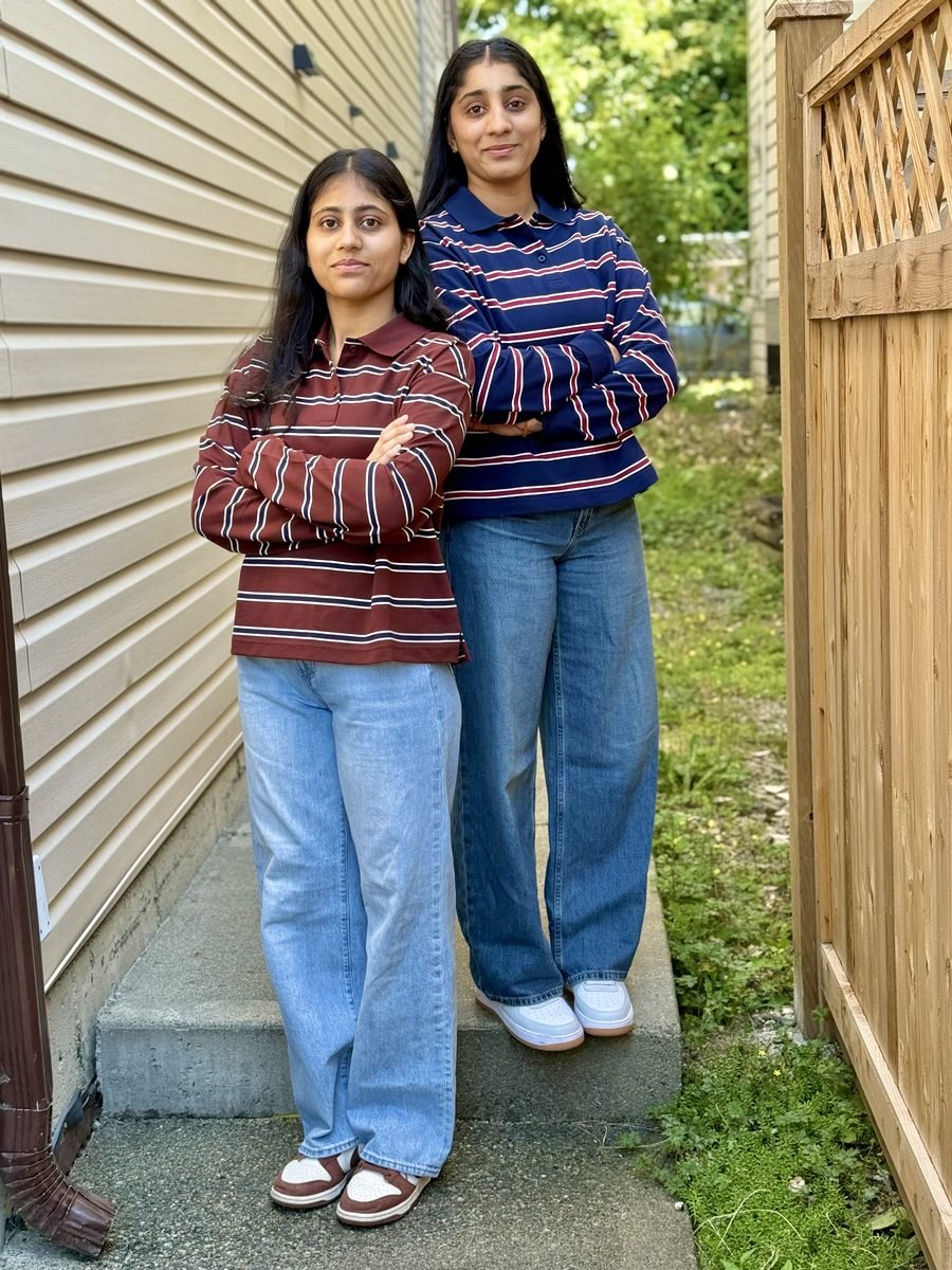 Harpreet standing on a step beside a house and a wooden fence