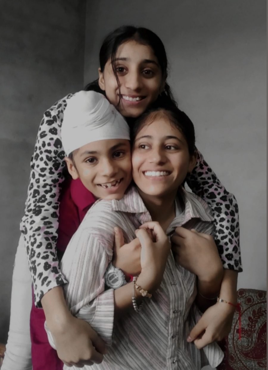 Harpreet smiling with her arms around two young family members