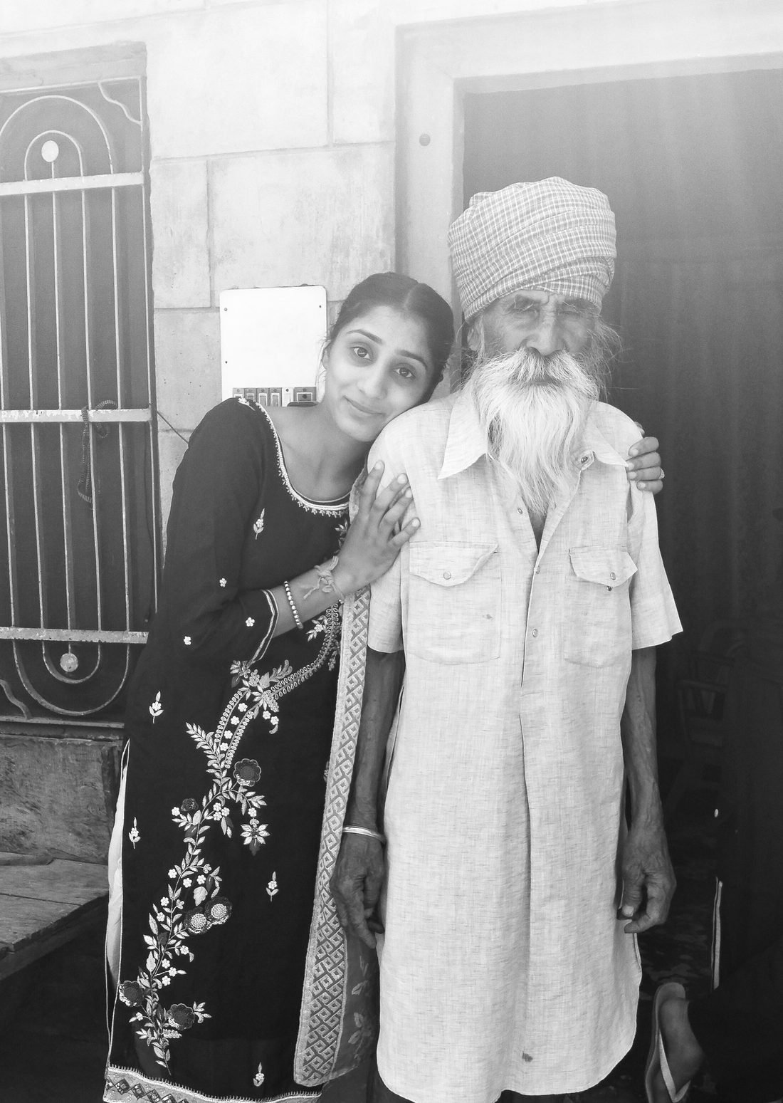 Harpreet Kaur leaning her head on the shoulder of her Nana, an elderly Punjabi man in a turban and long white beard, in a black and white photograph